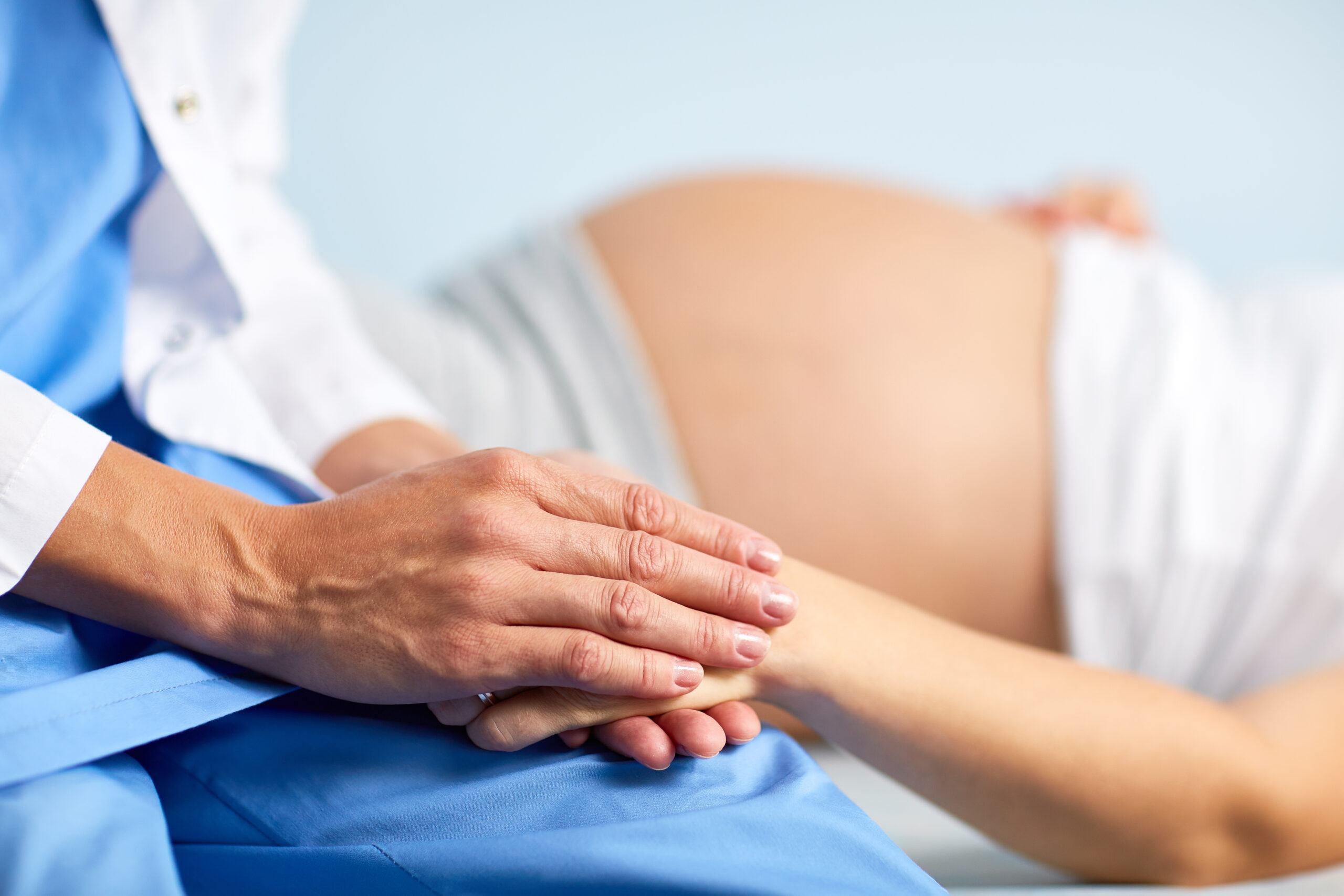 Pregnant patient holding hands with a healthcare provider
